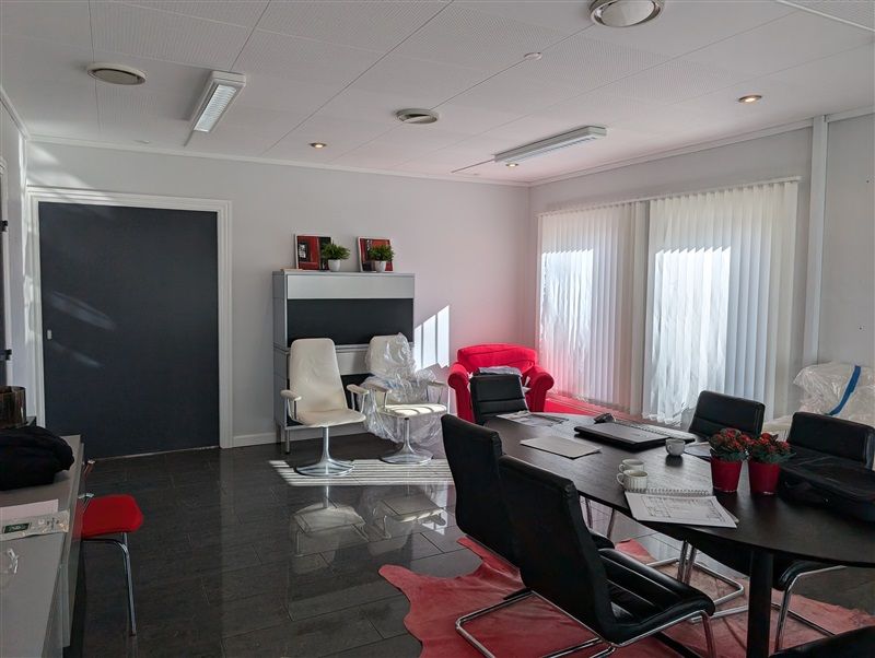 Elegant møbleret kontor med skrivebord, lysestole, rødt skur og hvide gardiner samt lysekroner i loftet