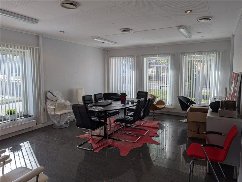 Erhvervsejendom med møbelryggede kontorer, runde borde og stole, vinduer med lysegardiner og et gulv med granitfliser