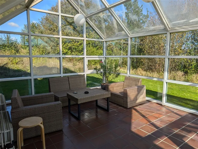 Solrige rum med grønne skurvægge og gulv med brune fliser og sofaer med træbord og potteplante