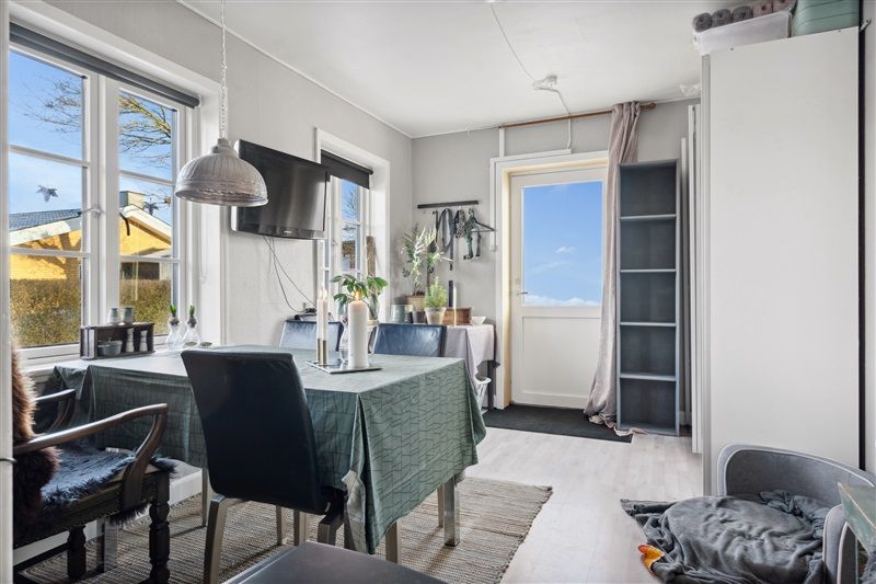 Velholdt stue med lyse vindue med en stuebord, to stole, sofa, hylde og et fjernsyn