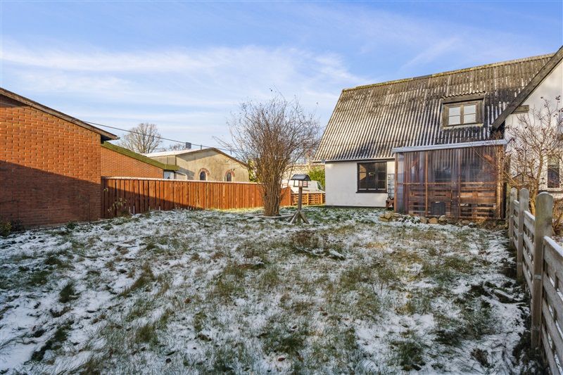 En snesneget dækket gårdhave med en række træer og en højtliggende veranda med et tag af metalplader