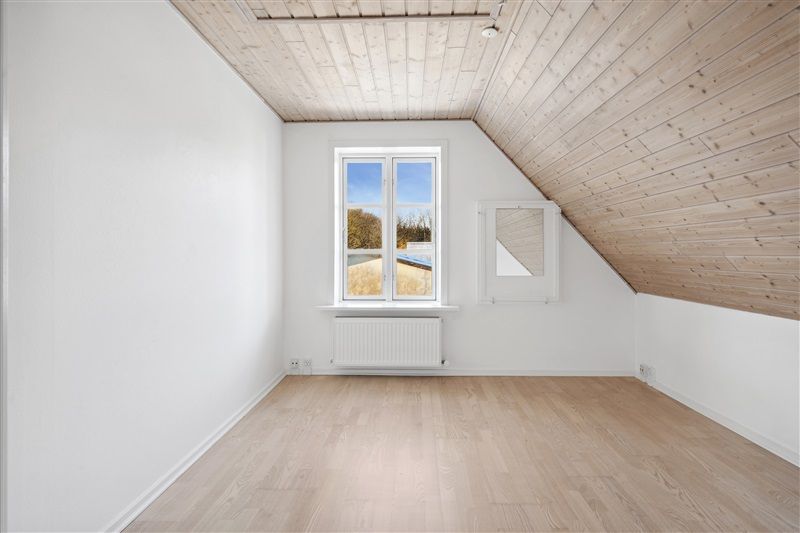 Udlejningsejendom i Farre med hvide vægge og lyse trægulve. Lys og rummelige værelser med lyseglasvinduer og lysekroner.