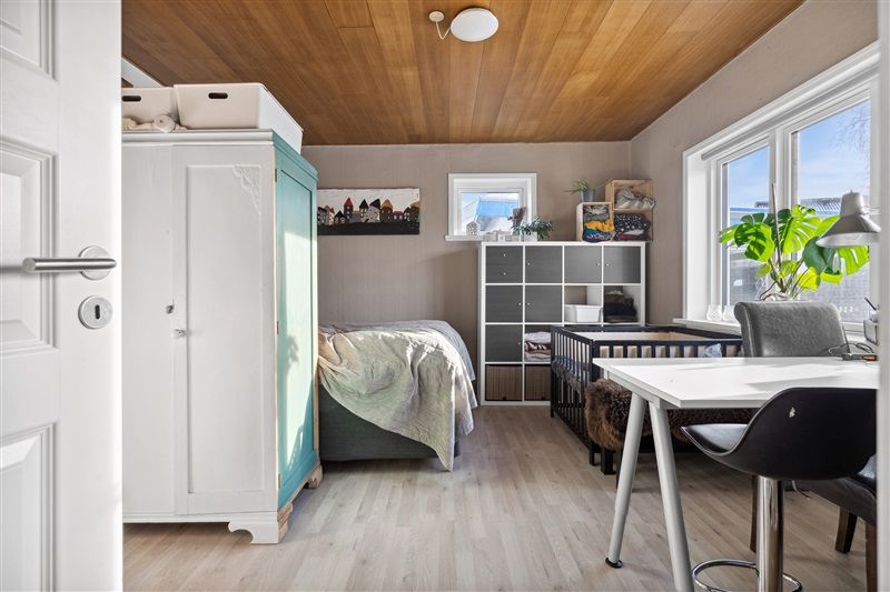 Køkken med højt loft og køkkenhylde, et lille skrivebord og en børneseng og voksne seng med smukke sengeforhæng