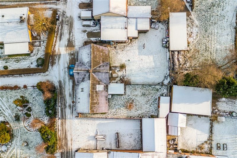 Om vinteren står et stort anlæg med flere huse og bygninger, alle dækket af sne og med skilte på deres tag