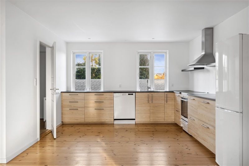 Moderne køkken med lysegul træpanelering og hvide vægge, store vinduer og integreret hvidevarer og apparater