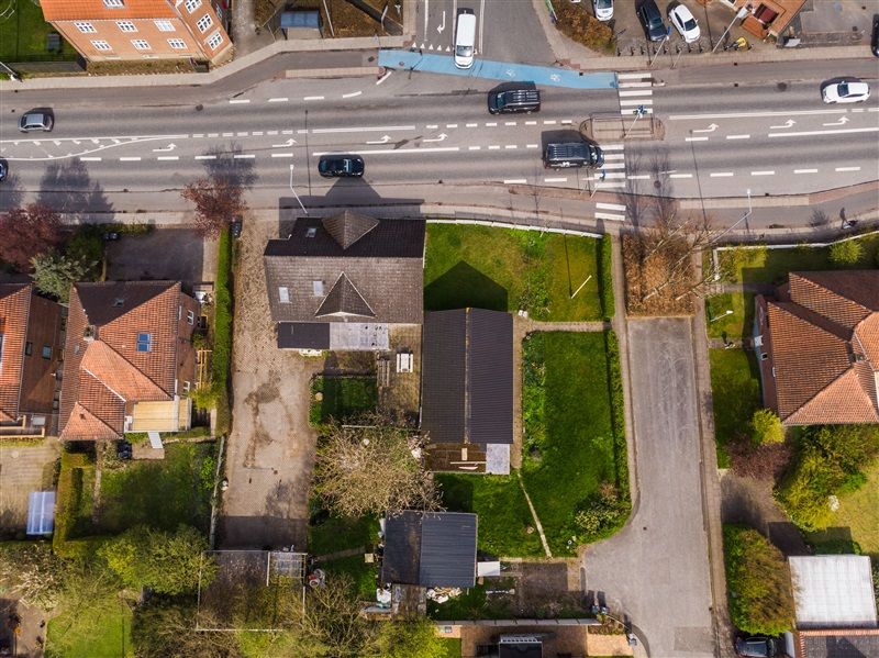 Flyfoto af et område med mange huse og biler, der kører langs vejene og krydserne