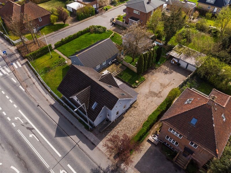 Hus med tagrammer og parkeringsplads i kvarter med vej og fortov med vejvisningstavler