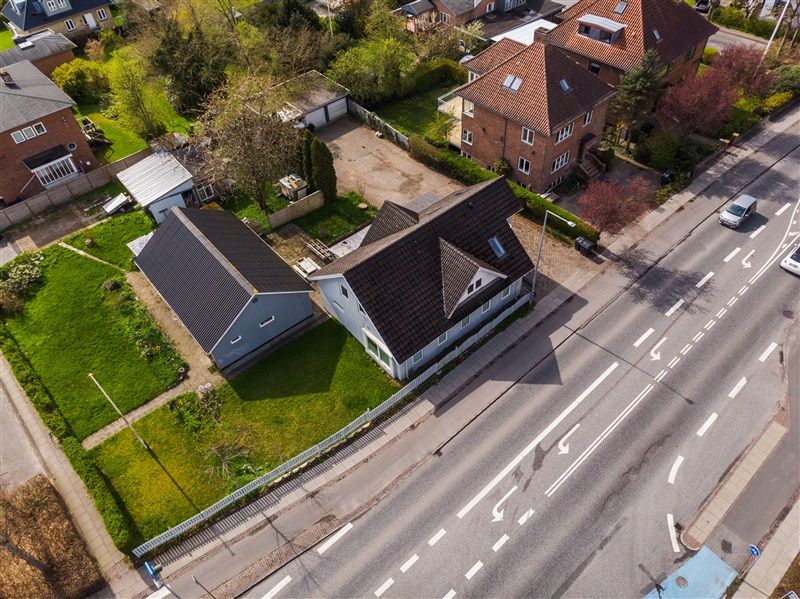 Luftfoto af en gade med flere huse og et køretøj parkeret på siden