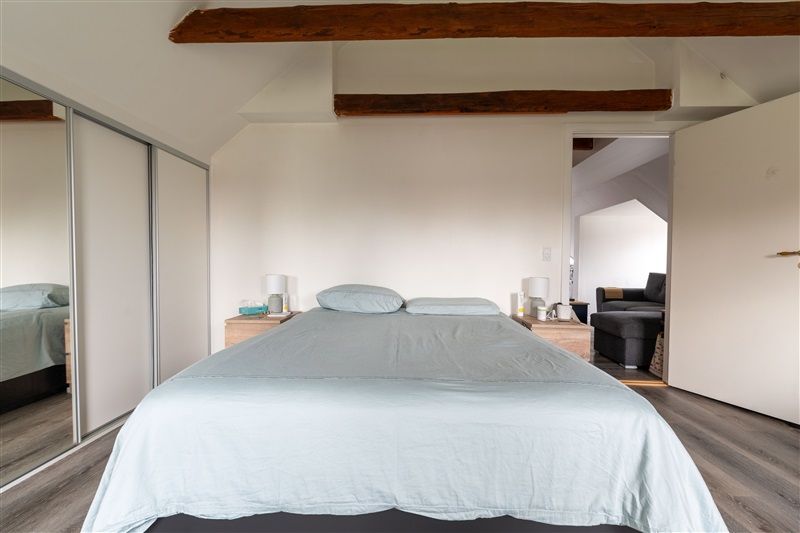 Et soveværelse med lyseblå dynebetræk, to hvide puder, to lamper og en lukket dør