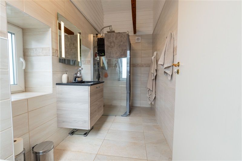 Hvidt badeværelse med spejl, håndklæde og sæbe. Toiletpapir, opvask og gulvtøj.