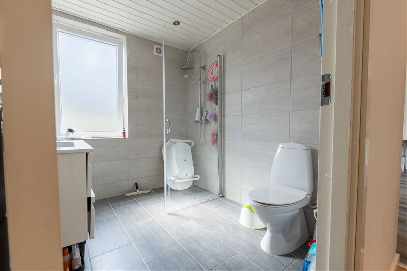 Hvidt toilet og toiletbrille med skærm i badeværelse med vinduesglas og vinduesruder