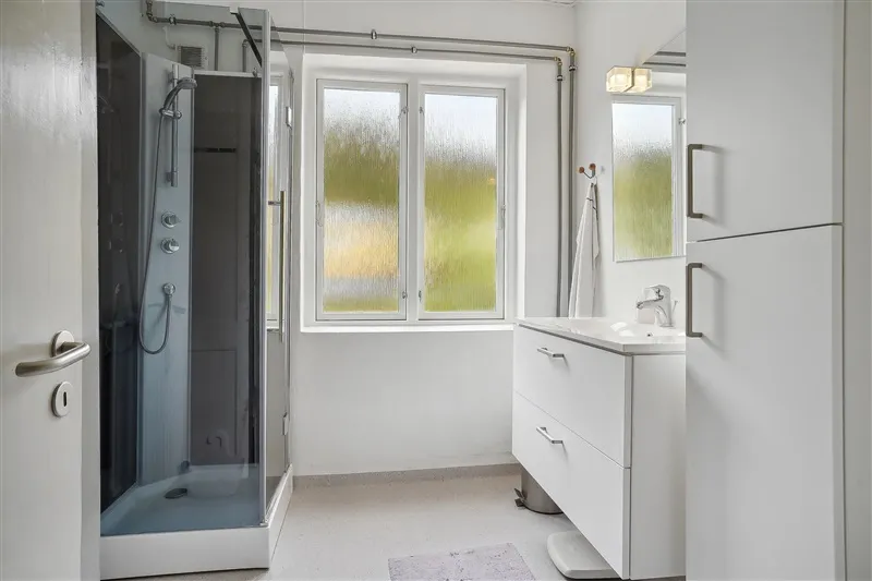 Inden for et rent badeværelse med hvidt bord og spejl samt høj kvalitet badeværelsesudstyret