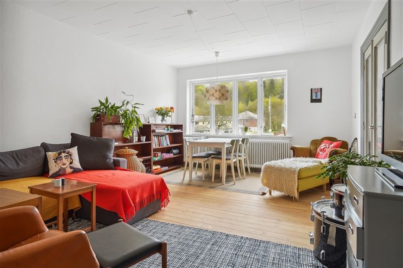 Velholdt lejlighed med lyse, lyse møbler og en stor sofa med puder og tæppe