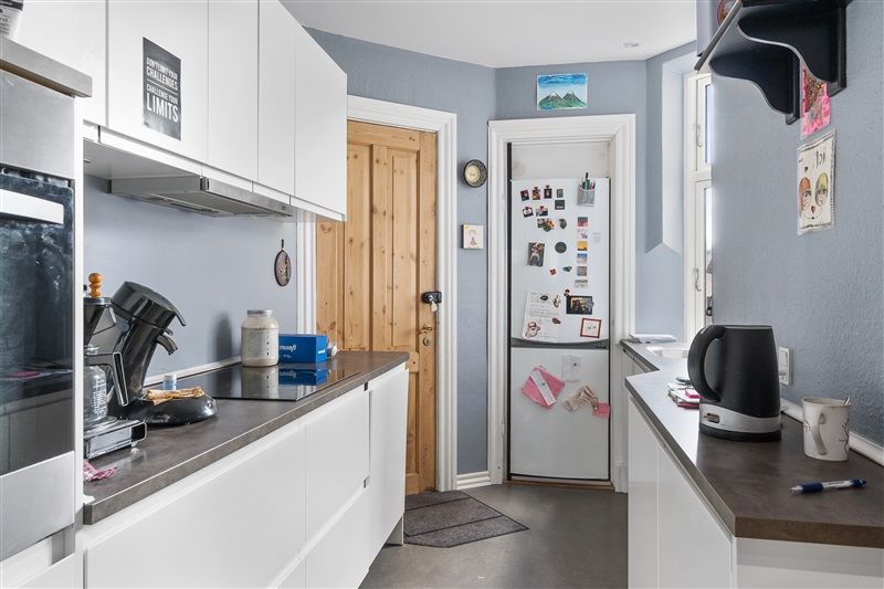 Et moderne køkken med hvidt køkkenskabe og en indbygget ovn med en kedel på den højre side og en køleskab med mange