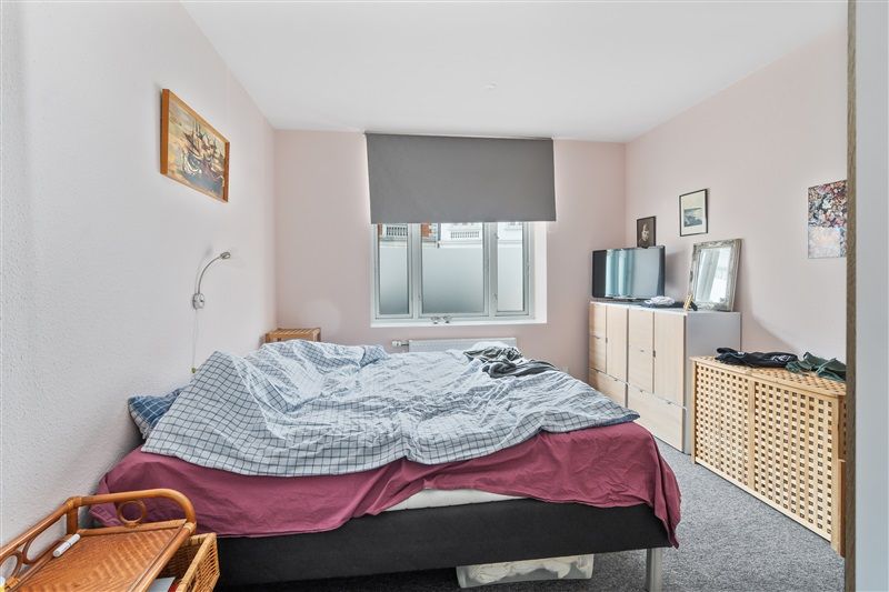 Et soveværelse med en enkeltseng og pude, et skab og en spejl, og en maleri på væggen