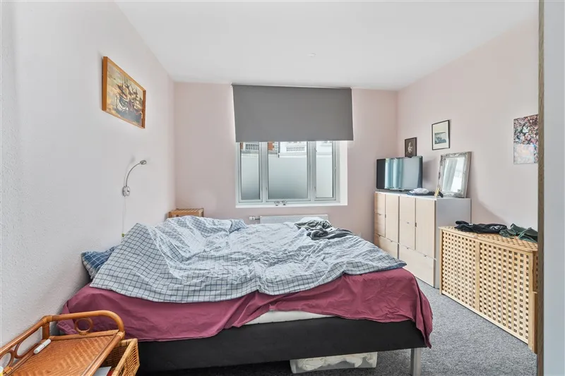 Et soveværelse med en enkeltseng og pude, et skab og en spejl, og en maleri på væggen