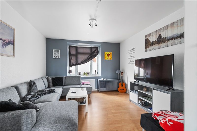 En værelse med en stor gry sofa og tv samt en hvid bord og en gul klaver.