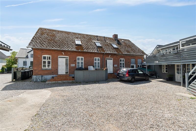 Lejlighedsbygning med garage og parkeringsplads, gul og rød mursten og hvide vindueskarmér, i en fredelig bygning med grønne