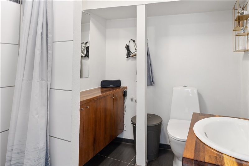 Alt-tekst: En moderne hvid badeværelse med to toiletter, en stor spejl og en høj, guldfærget hylde med lysekroner og andre