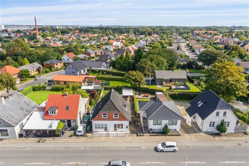 Gade med rækkehuse og vejkryds i Kolding, biler parkeret og på kørsel, træer og grønne arealer