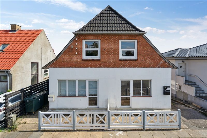 Huset med en hvid og rød facade og to vinduer samt en hvid indgangsdør og en hvid stang udenfor