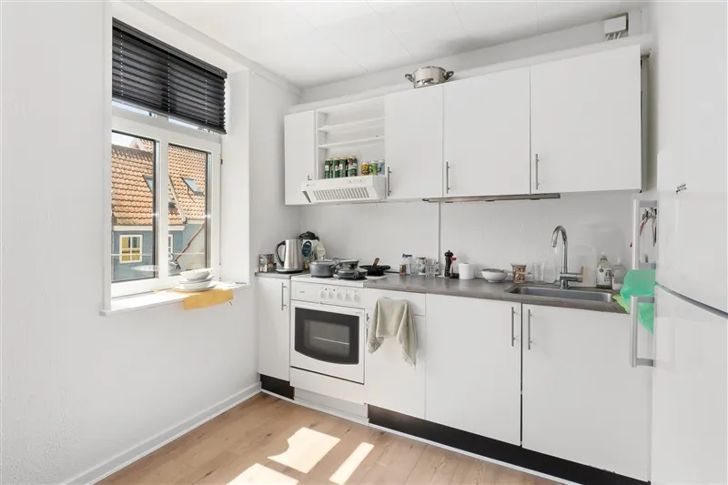 Hvid køkken med moderne design, højloft, keramiske gulve og lysevinduer med gardiner