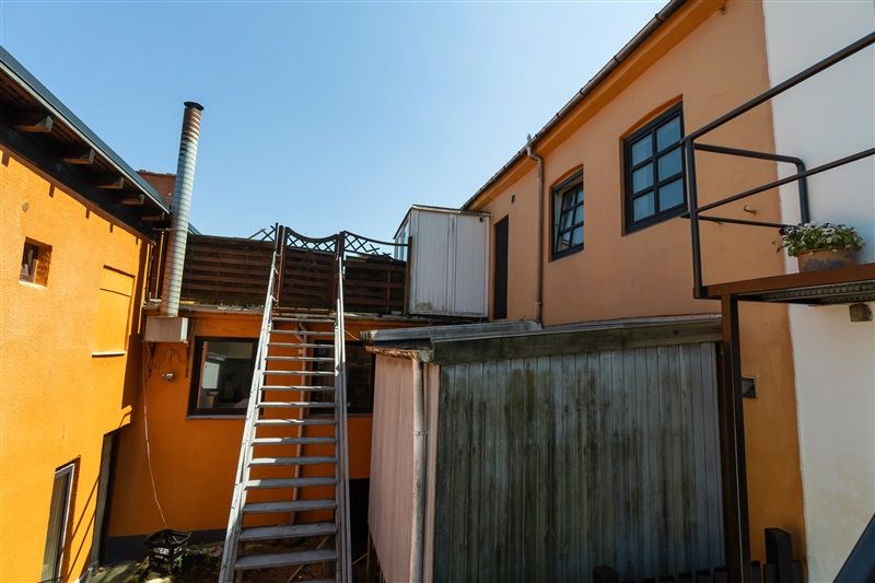 Huset med gul væg og vinduer og trætrappe til loftsetagen og et gult tag