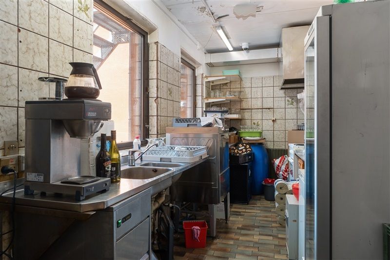 Et køkken med en kaffemaskine, en flaske og en række rengøringsartikler og beholdere