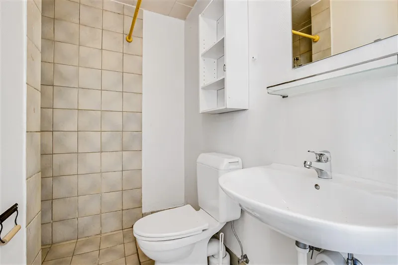 Et lille badeværelse med en hvid toilet, hvid vask og et spejl med en håndtag