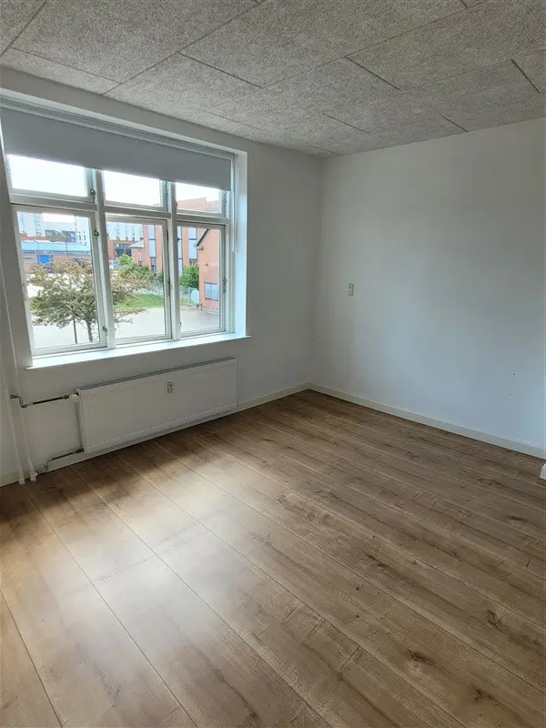 Investeringsejendom med renoveret interiør og trægulv Frederiksgade 97, Fredericia. Vindue med gardiner og solskin i rummet