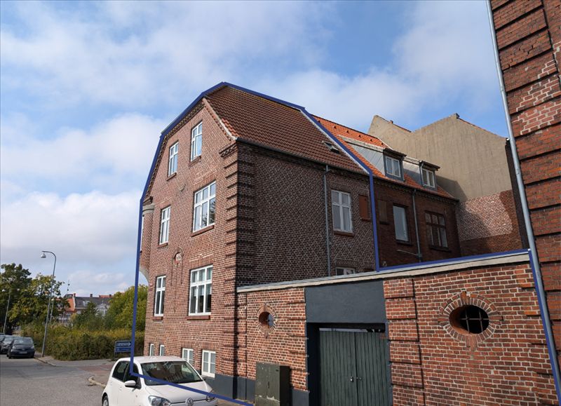 Bred røde murstensbygning med tagrenne og to runde vinduer og højt skrånende tag