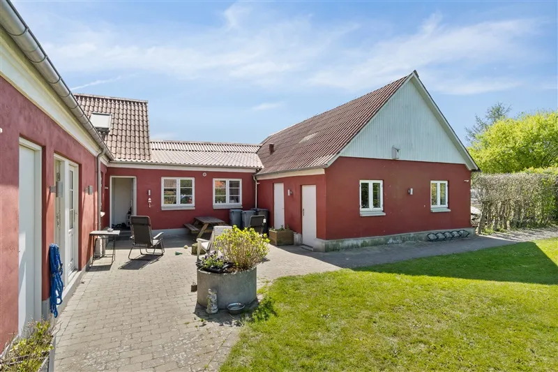 Totalrenoveret og attraktivt hus med terrasse, kunstplante og møbler i en idyllisk have med græsplæne og skur