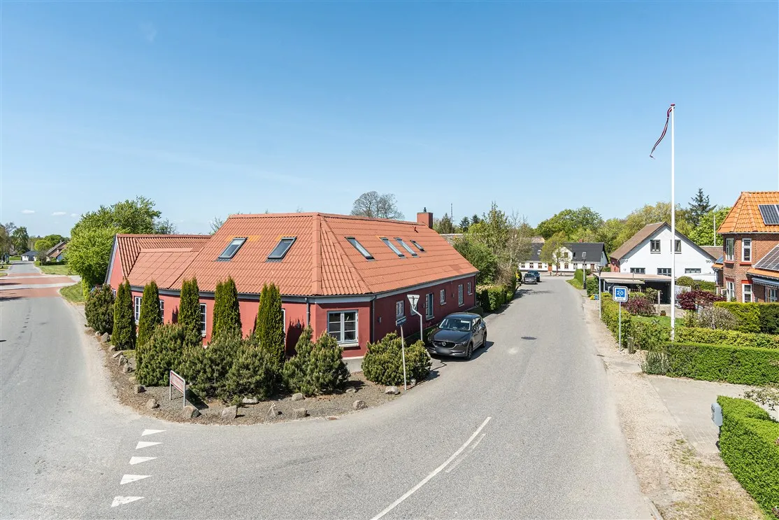 En rød bygning med solceller på taget og en bil parkeret udenfor i Herslev Bygade 1A, Fredericia