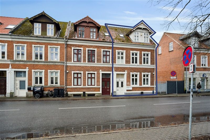 En rækkehuslejlighed i røde mursten med mange vinduer og to skråt liggende gavle i Fredericia
