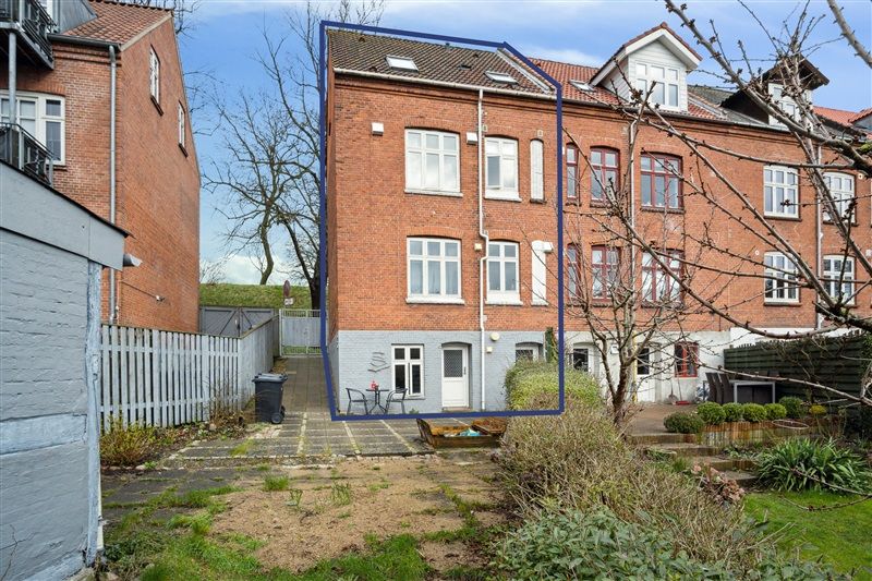 Flot og velholdt tre-etagers lejlighed i røde mursten, have, terrasse og parkeringsplads.