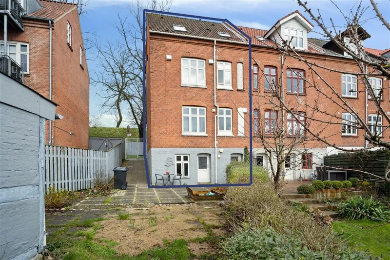 Flot og velholdt tre-etagers lejlighed i røde mursten, have, terrasse og parkeringsplads.