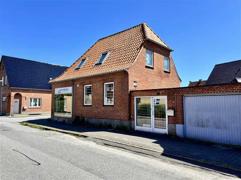 To murstensbygninger med tagrammer og vinduer langs Thorsvej i Fredericia. Lysblå himmel med få skyer.