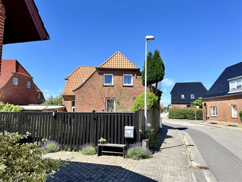 Huse med røde tag i en fredelig gade i Fredericia med en høj skråning og lysegrå asfalt.