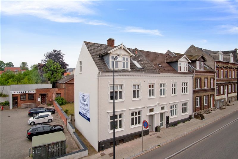 Renoveret og optimeret udlejningsejendom i Fredericia med parkeringsplads og solrig terrasse, samt banner med teksten