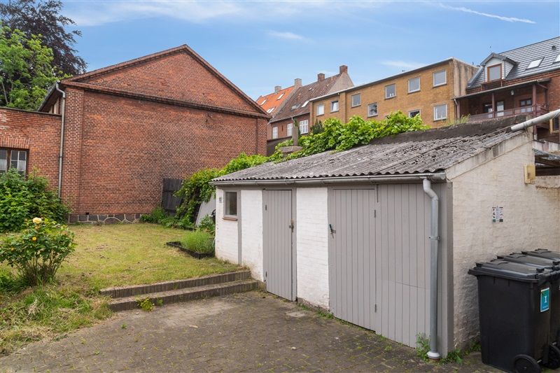 Op ad trapper til garage og tilstødende bygning med rød mursten og terrasse med planter