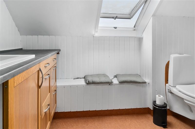 Rent og minimalistisk badeværelse med hvidt loft og vægge, lysegråt bordplad og tre træskuffer