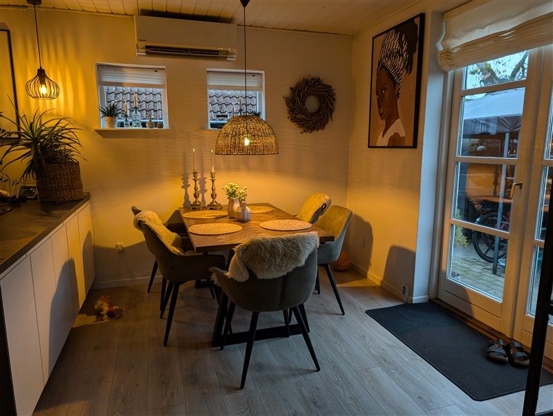 Skandinavisk indretning med lyse farver og smukke møbler i en lille stue med åbent køkken og en glastør til gården