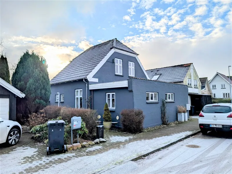 Købehus med stor have i Havepladsvej 50 i Fredericia. To biler parkeret foran og udsigt til solnedgang. Have med buske og