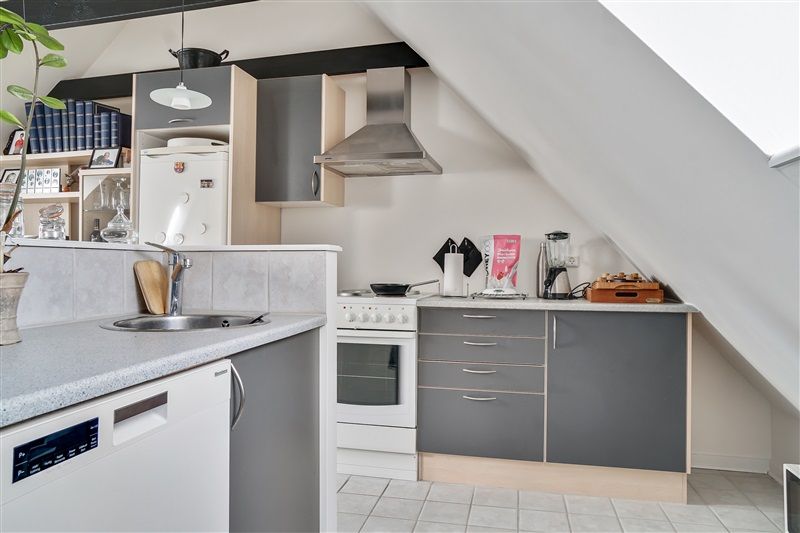 En hyggelig stue med loft med indbygget komfur, vaskemaskine, komfur, køleskab og spiseplads med bord og stole