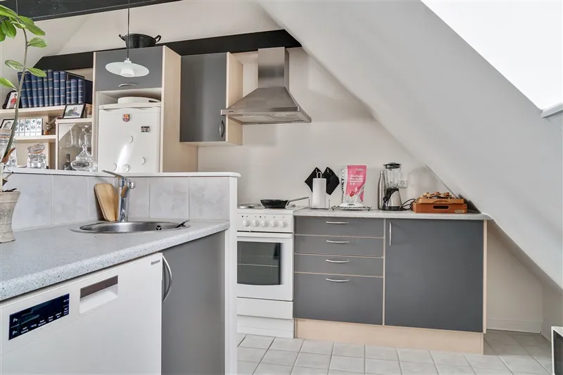 En hyggelig stue med loft med indbygget komfur, vaskemaskine, komfur, køleskab og spiseplads med bord og stole