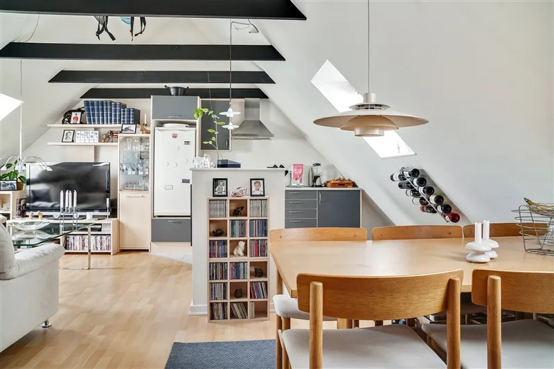 Et køkken med højloft og moderne møbler, hvor man kan se en bøjet stol, et bord og lysekroner