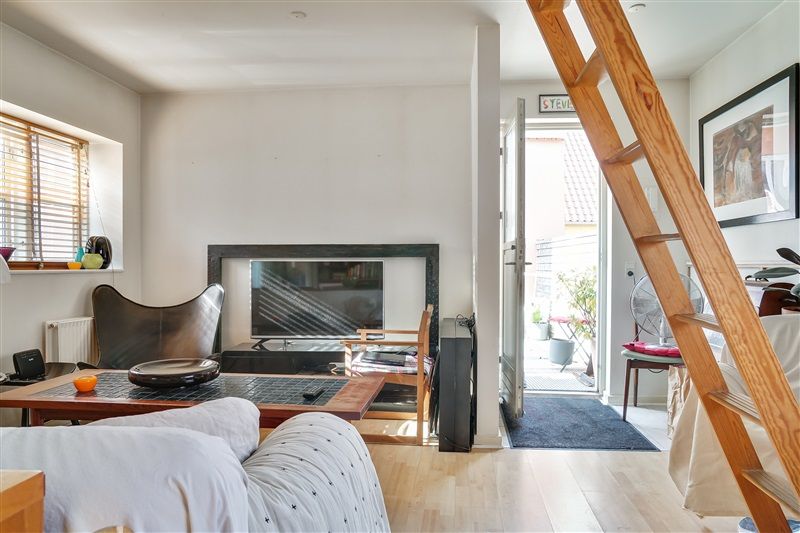 Lejlighed med lyse, moderne interiør og trætrappe, sofa, tv og vinduer med gardiner