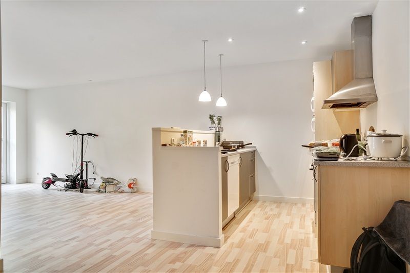 Køkken med højloft, lysekroner, øverstående ekstraktor, skabe, komfur, ståbrædder og scooter i enden