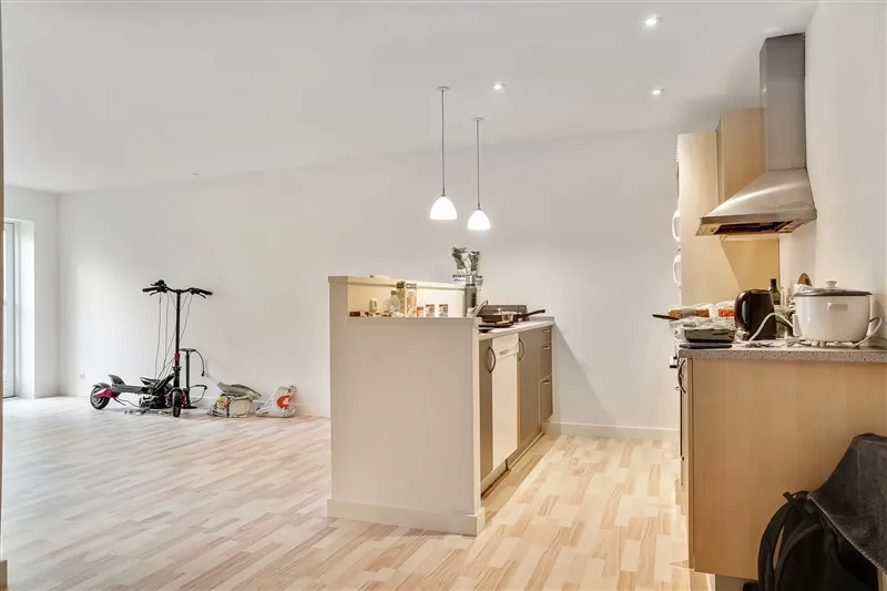 Køkken med højloft, lysekroner, øverstående ekstraktor, skabe, komfur, ståbrædder og scooter i enden