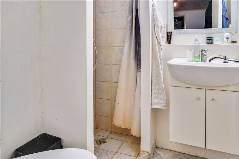 Hjørnebadeværelse med hvidt badekar og håndklæde, hængende i et hjørne, med hvidt vask og spejl på væggen